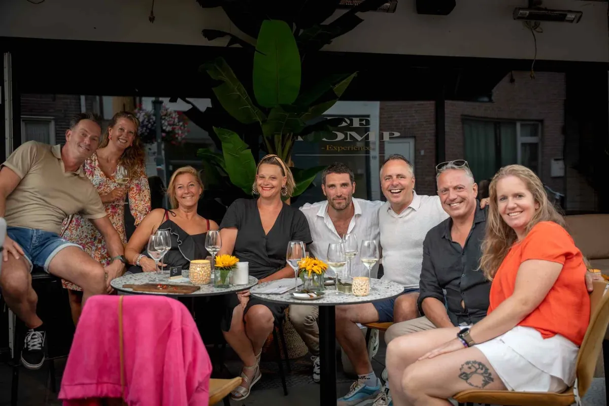 Een groep gasten aan een lange tafel bij Blend