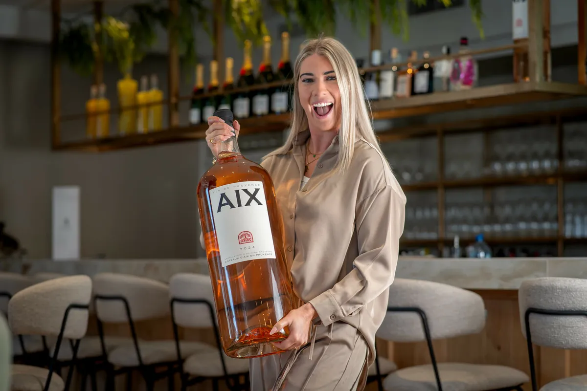 Een medewerkster van Blend met een grote fles AIX rosé voor de wijnkast