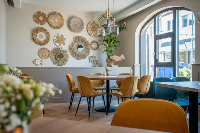 Ronde tafel met oker fluwelen stoelen onder een wand vol rieten manden